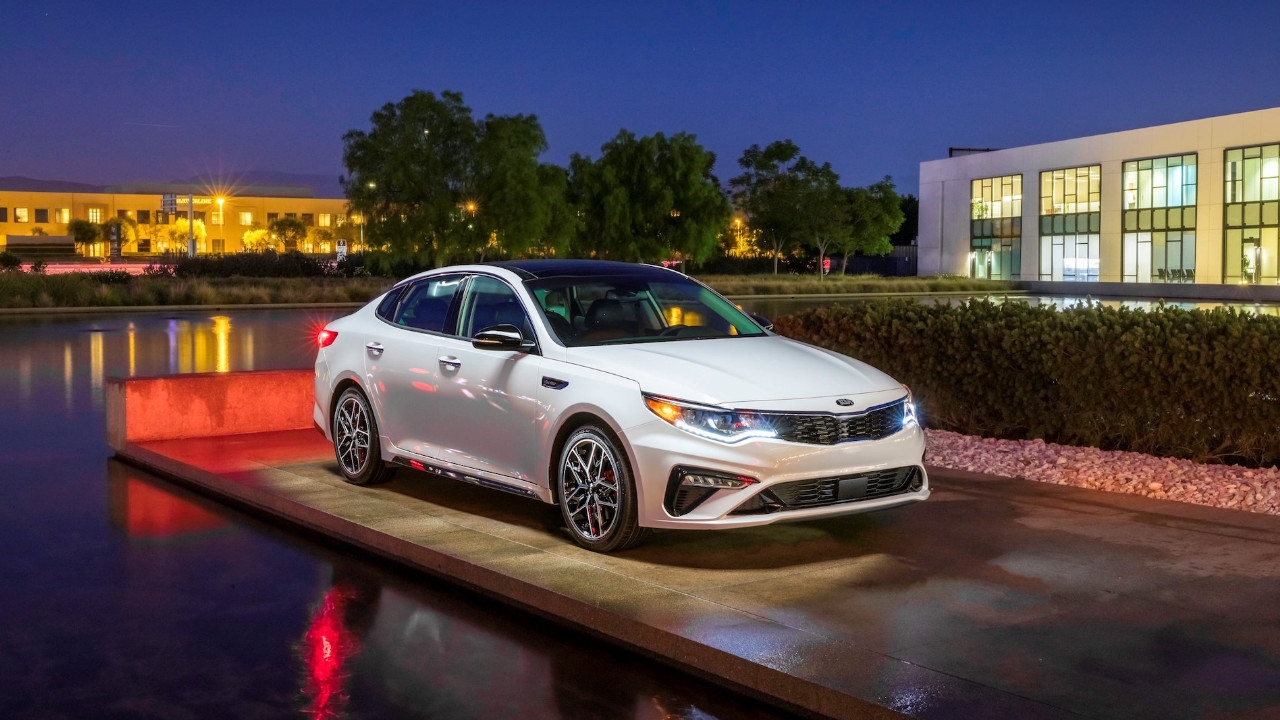 vue latérale avant d'une Kia Optima 2019 en ville le soir