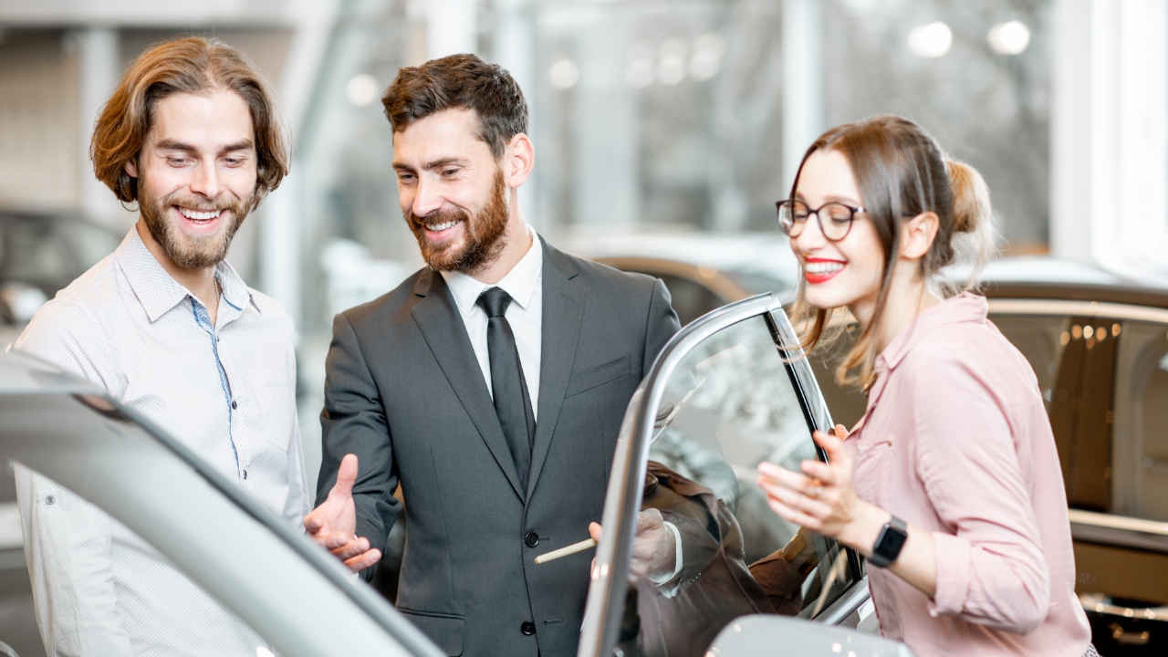 couple avec un vendeur devant un véhicule