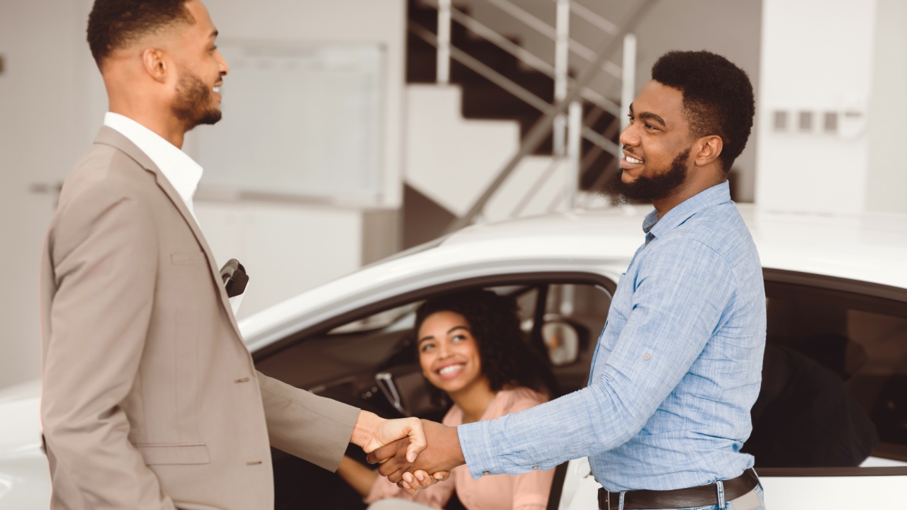 couple discutant avec un vendeur devant un véhicule