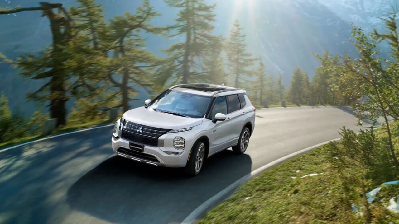 vue latérale avant d'un Mitsubishi Outlander 2024 sur une route en forêt