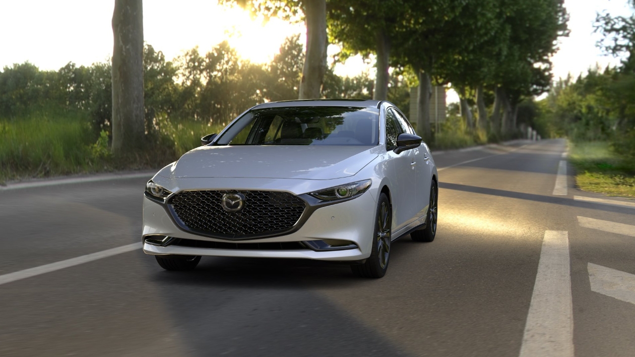 vue latérale avant d'un Mazda Mazda 3 2024 sur une route de campagne